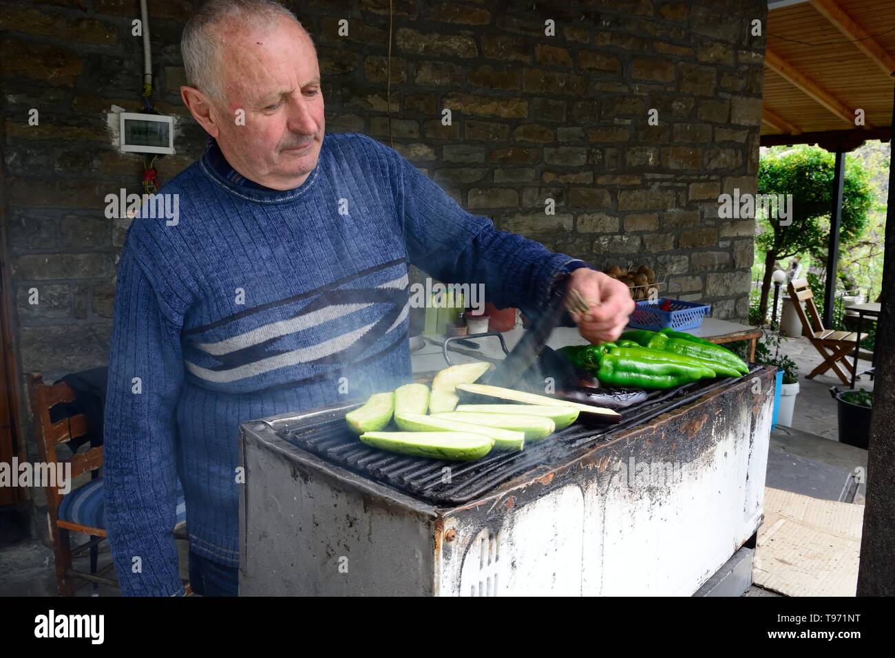 Uomo albanese per grigliare verdure alla brace per pranzo presso un lato strada ristorante Abania Foto Stock