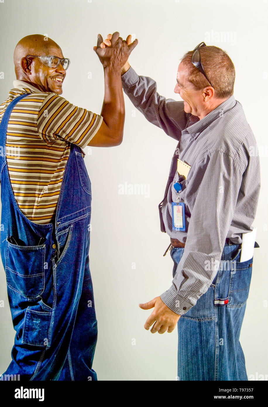 E caucasici americano africano di manutenzione ferroviaria operai condividono un ridere interracial handshake a Los Angeles. Foto Stock