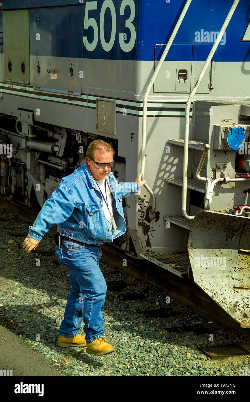 Dopo essere arrivati a Los Angeles cantiere ferroviario, un treno ingegnere indossare occhiali di sicurezza e stivali si arrampica verso il basso la scaletta del suo locomotore. Foto Stock