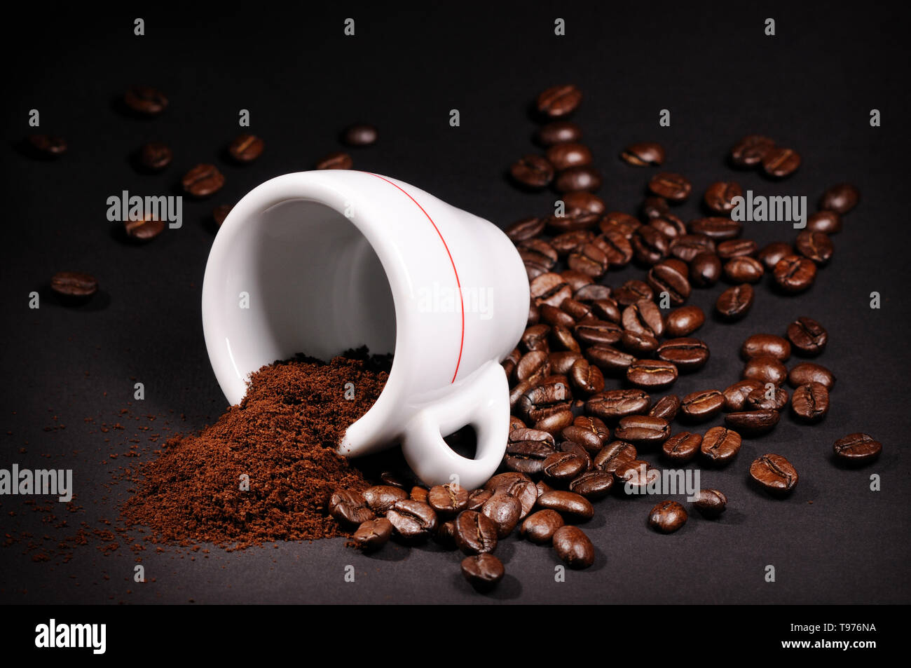Cup con mucchio di chicchi di caffè su sfondo nero Foto Stock