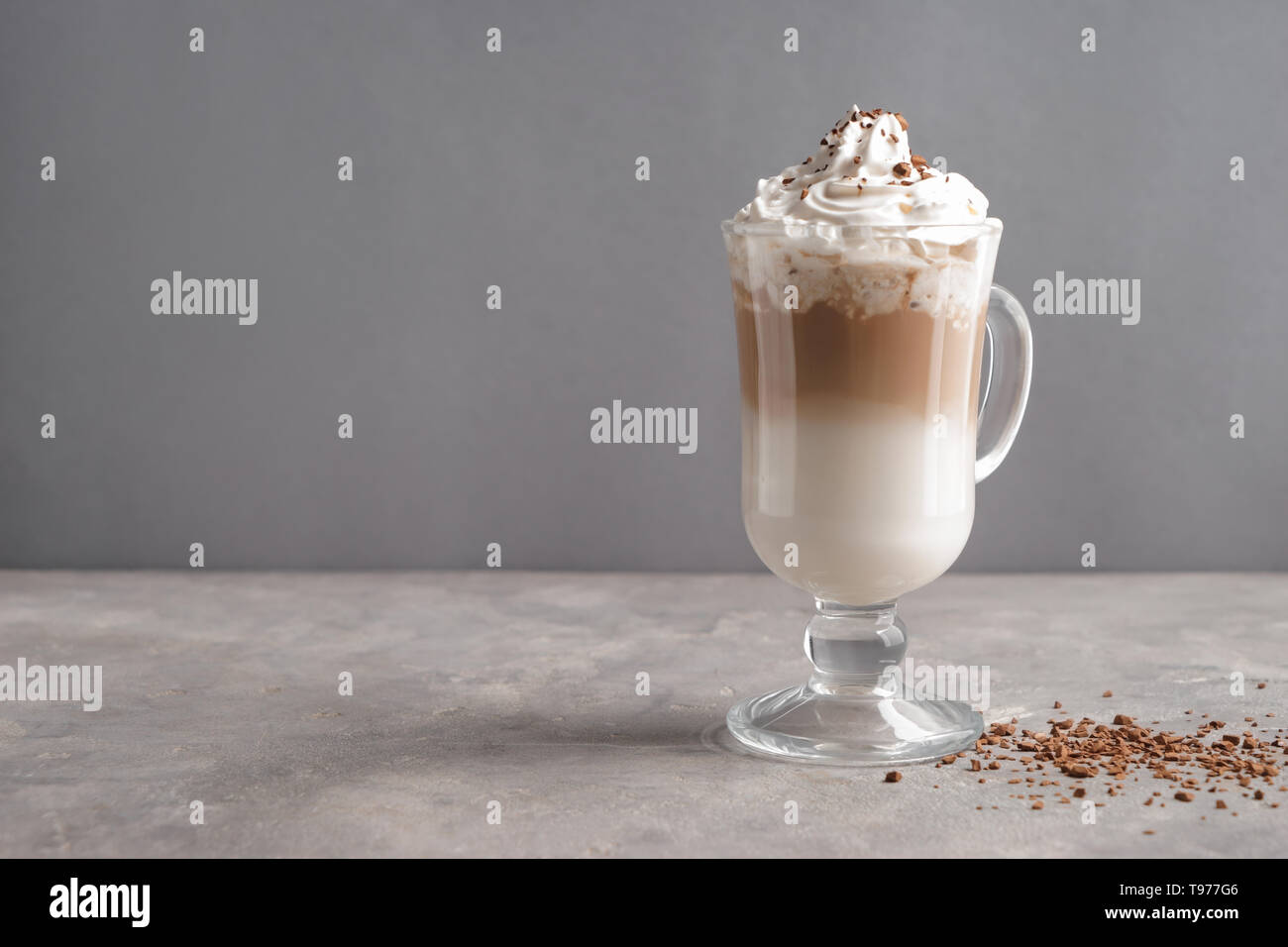 Bicchiere di caffè freddo coperto con panna montata sulla tabella grigia Foto Stock