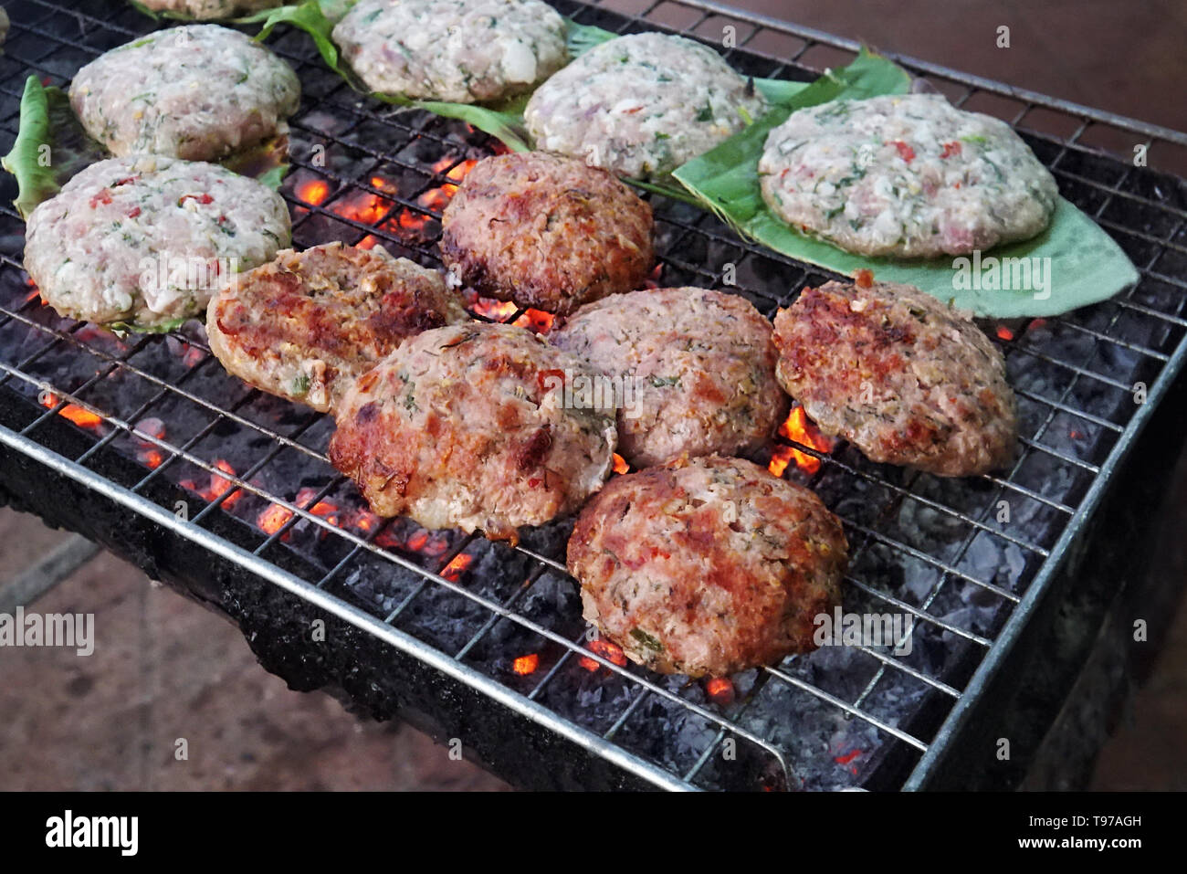 Il rubicondo costolette fritte su una foglia verde vengono fritte su strada su un grill. Cucina di strada in Asia. Preparazione della carne di manzo cotoletta con spezie sul grill per ha Foto Stock