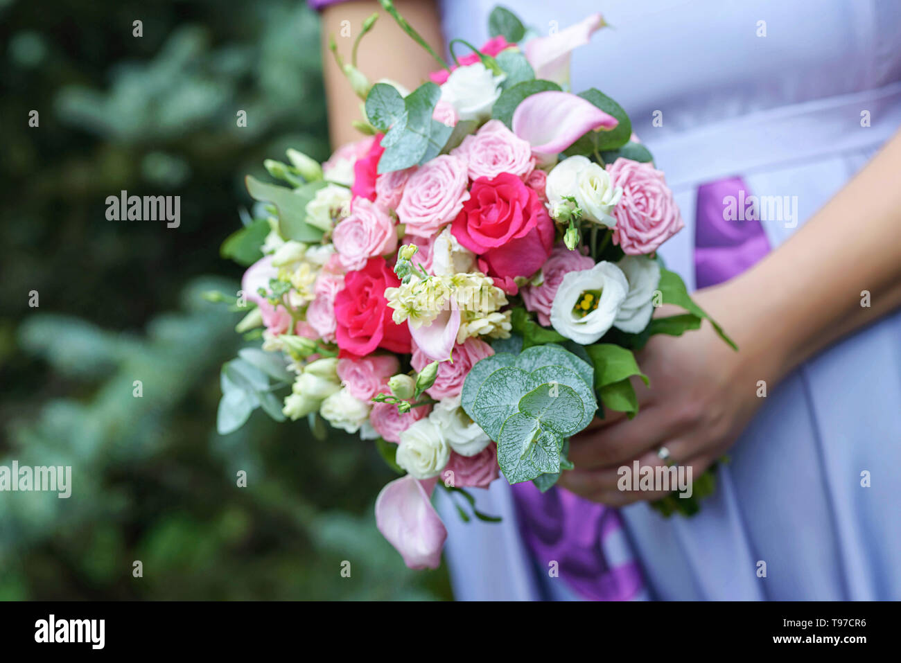 Femmina caucasica guest o damigella indossando un lilla abiti estivi che mostra un grazioso baby bump e tenendo un delicato sotto forma di libero bouquet Foto Stock