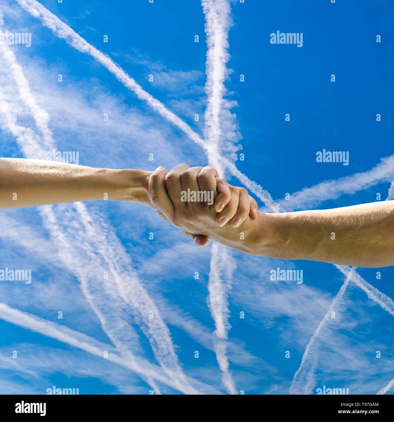 Primo piano di un uomo e una donna si stringono la mano sopra il bello blu cielo con contrails. Foto Stock