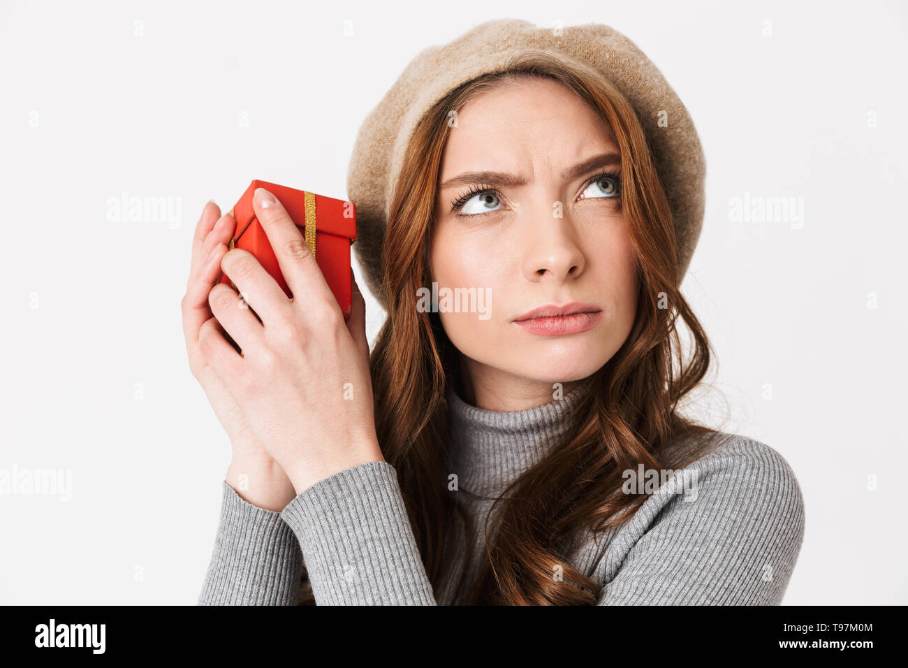 Foto di concentrato di donna 30s indossando hat azienda confezione regalo rossa isolate su sfondo bianco Foto Stock