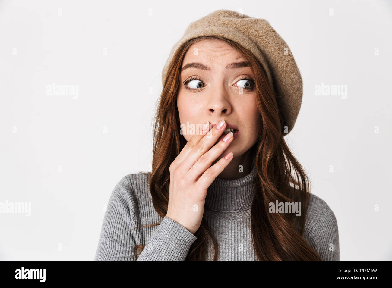 Ritratto closeup di paura donna 30s indossando hat terrificante e bocca di copertura isolato su sfondo bianco Foto Stock
