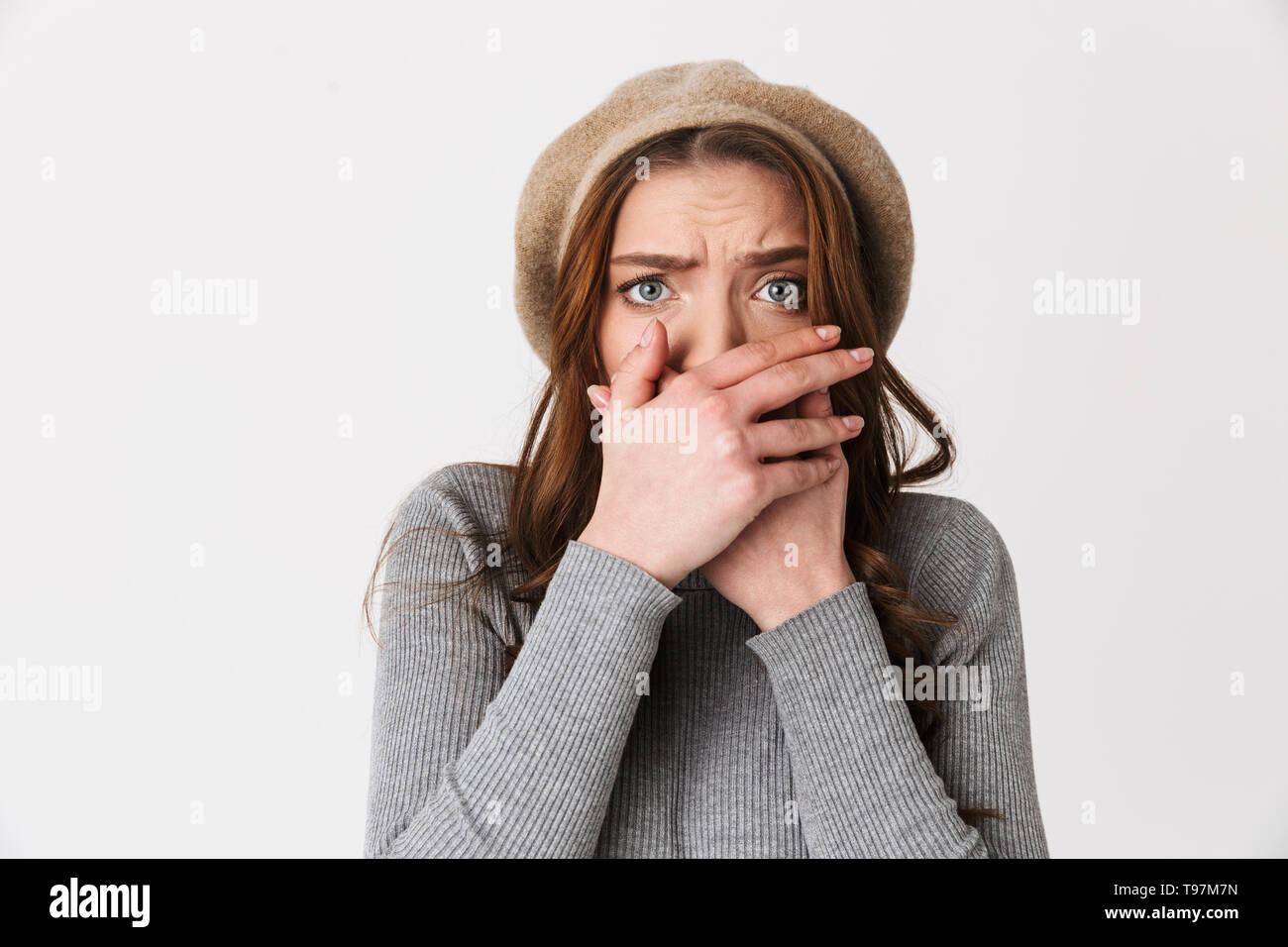 Ritratto di closeup donna scioccato 30s indossando hat terrificante e bocca di copertura isolato su sfondo bianco Foto Stock