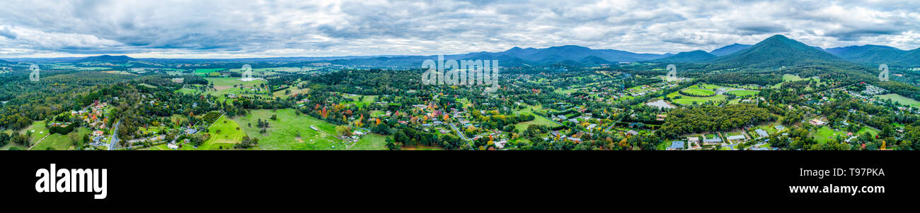 Ultra wide panorama antenna dello scenografico paesaggio rurale con case circondate da alberi, prati e montagne. Foto Stock