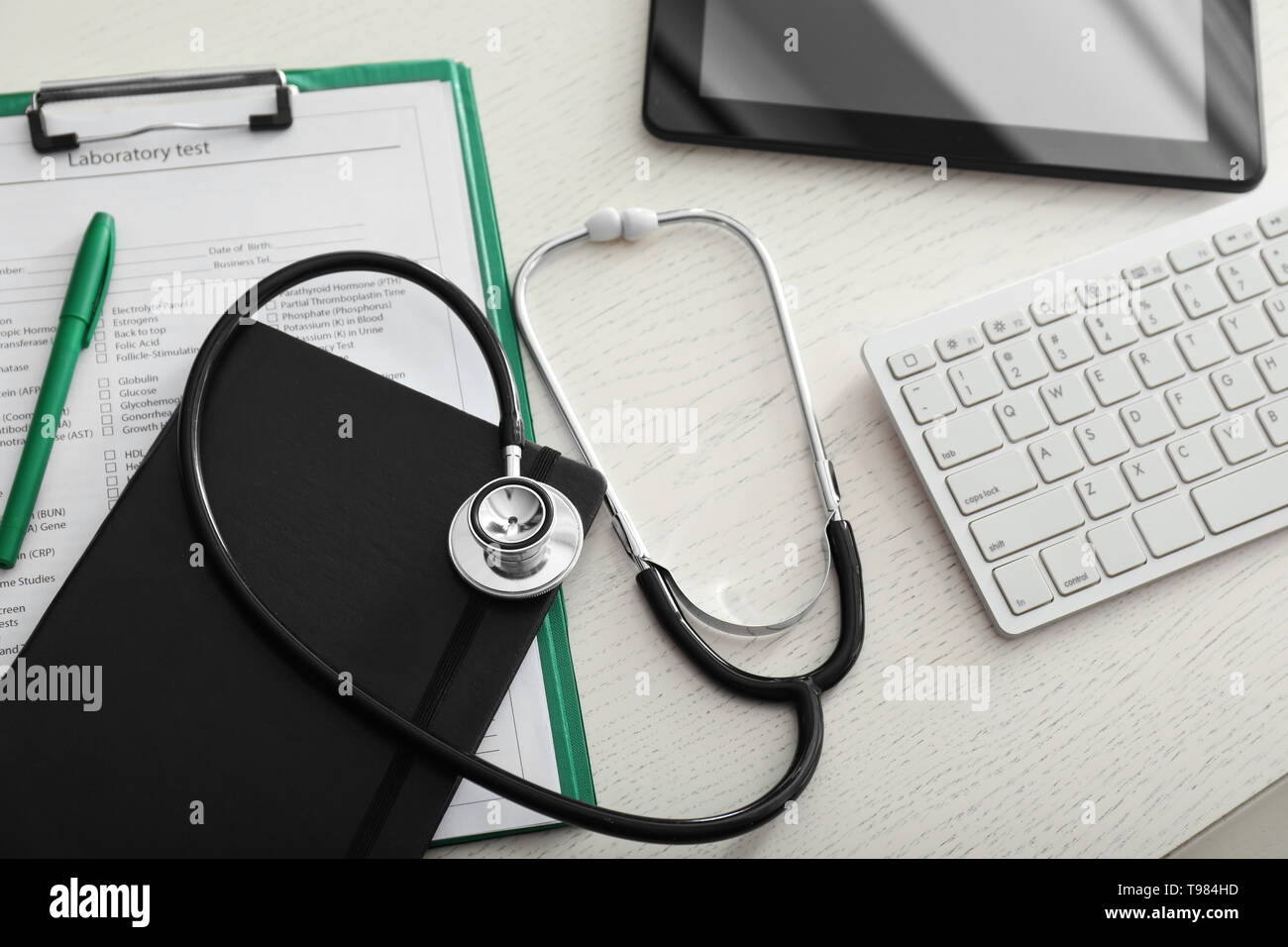 Uno stetoscopio con test di laboratorio modulo di richiesta e il computer sul tavolo del medico. Health care concept Foto Stock