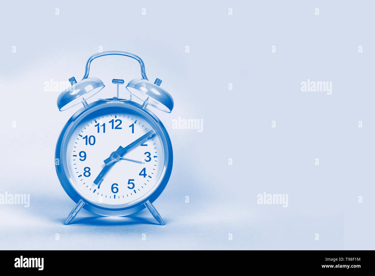 Vintage sveglia su uno sfondo rosa con spazio per copiare in un duo toni di blu immagine design Foto Stock