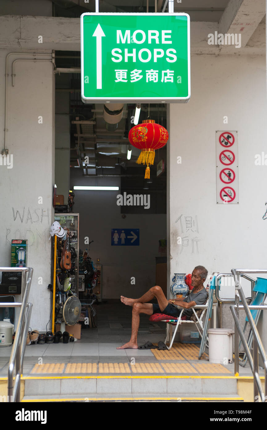 24.02.2019, Singapore , Singapore - un uomo più anziano si siede su una sedia a Singapore il quartiere di Chinatown e poggia. 0SL190224D016CAROEX.JPG [modello rele Foto Stock