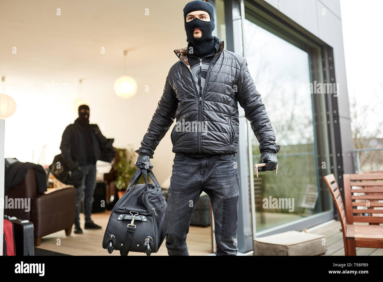 I ladri di fuggire con sacchi di bottino da una casa Foto Stock