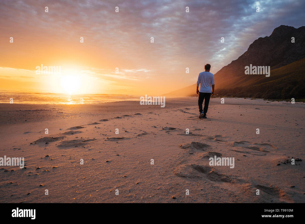 L uomo sulla spiaggia al tramonto, Western Cape, Sud Africa Foto Stock