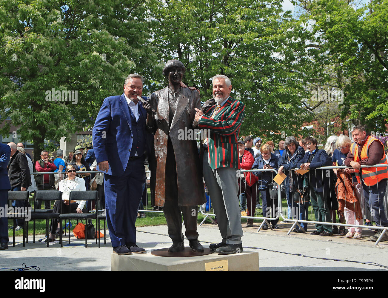 Una vita-size statua in bronzo del compianto comico, scrittore e attore, Victoria Wood è svelato in Bury town center dal comico Ted Robbins (sinistra) e suo fratello Chris Foote legno. Foto Stock