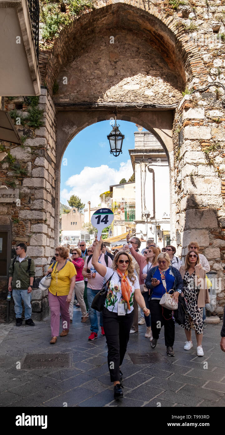 La guida turistica conduce un gruppo di visitatori attraverso porta Catania, corso Umberto, Taormina, Sicilia. Foto Stock