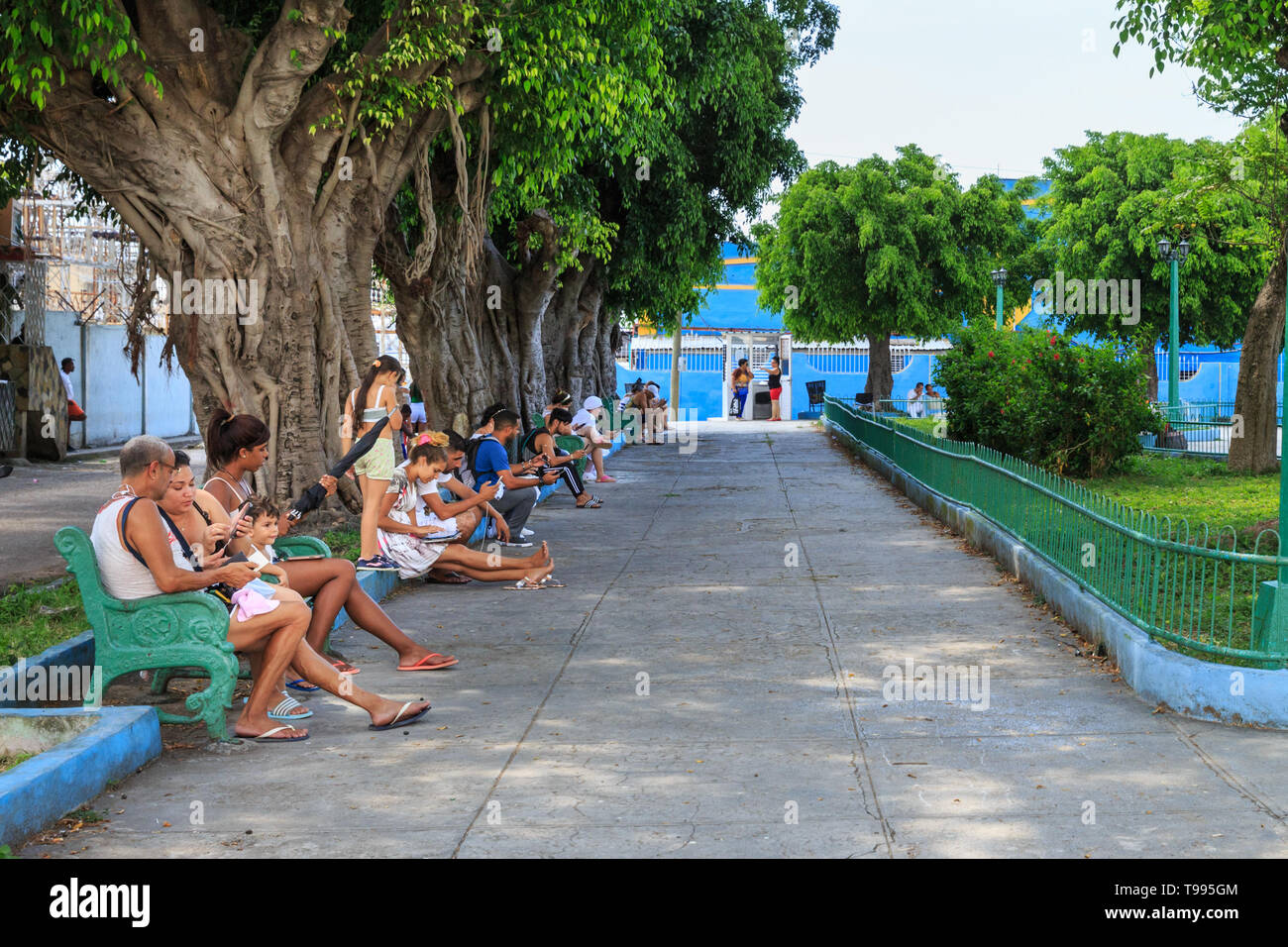 Il popolo cubano Relax, sedersi sulle panchine e navigare su internet con i loro telefoni cellulari a un hotspot wifi nel Parque De Las Madres, Regla, Havana, Cuba Foto Stock