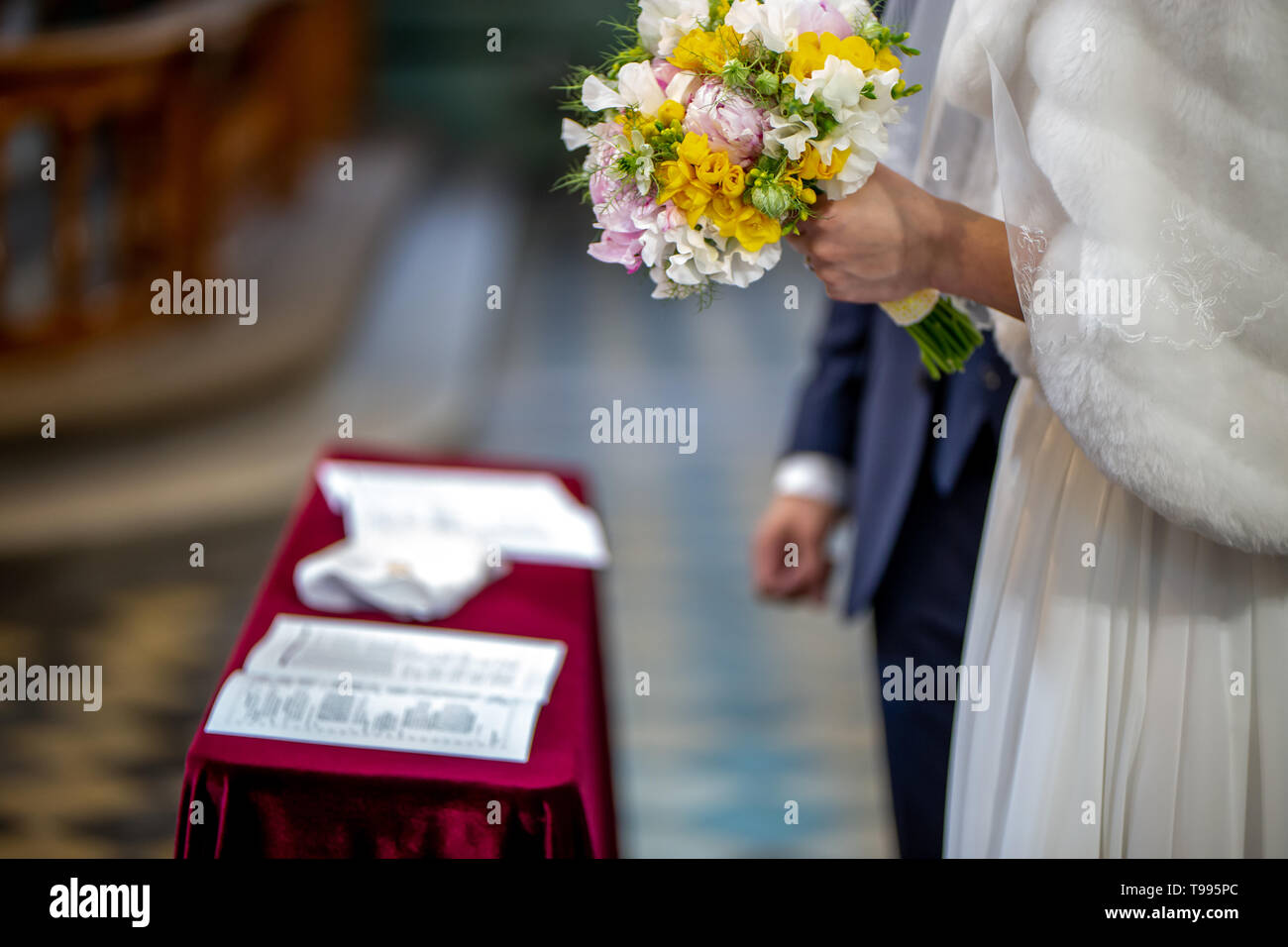 La sposa detiene un matrimonio bouquet di fiori nella sua mano. Il bouquet è composto di bianco, giallo e fiori di colore rosa. Matrimonio certificato di registrazione Foto Stock
