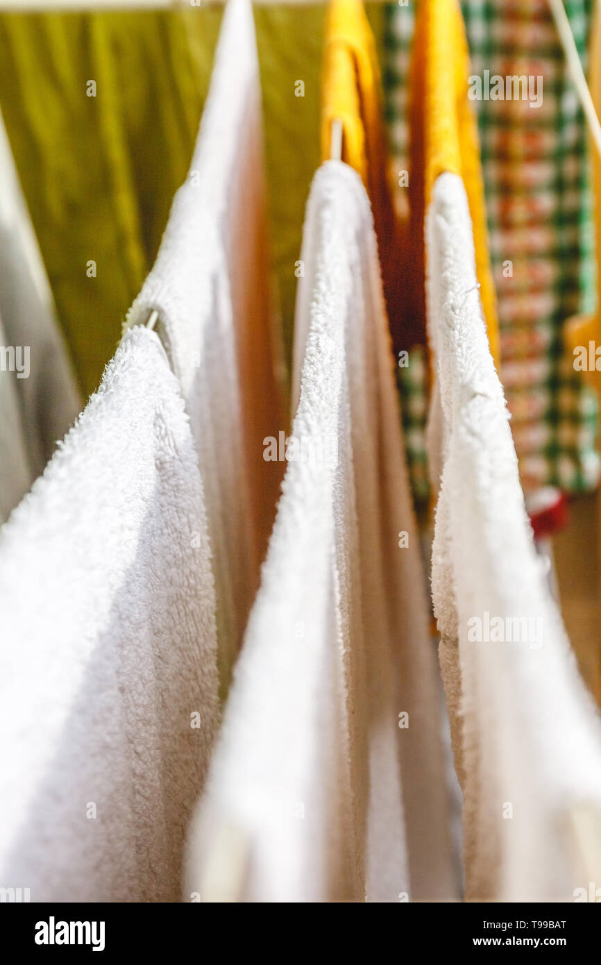 Bianche e colorate lenzuola e asciugamani per essere essiccato sul stendibiancheria. Foto Stock