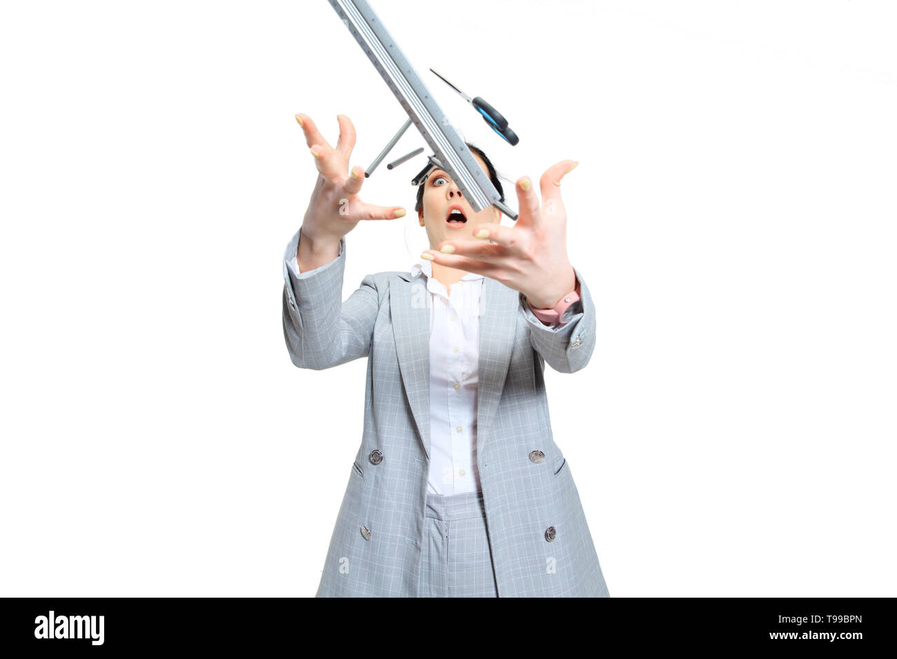 Giovane donna in abito grigio perdere la concentrazione. Tutto ciò che va storto e cade fuori delle mani, lei sta cercando di catturare i. Nozione di lavoratore di ufficio di guai, business, problemi e stress. Foto Stock