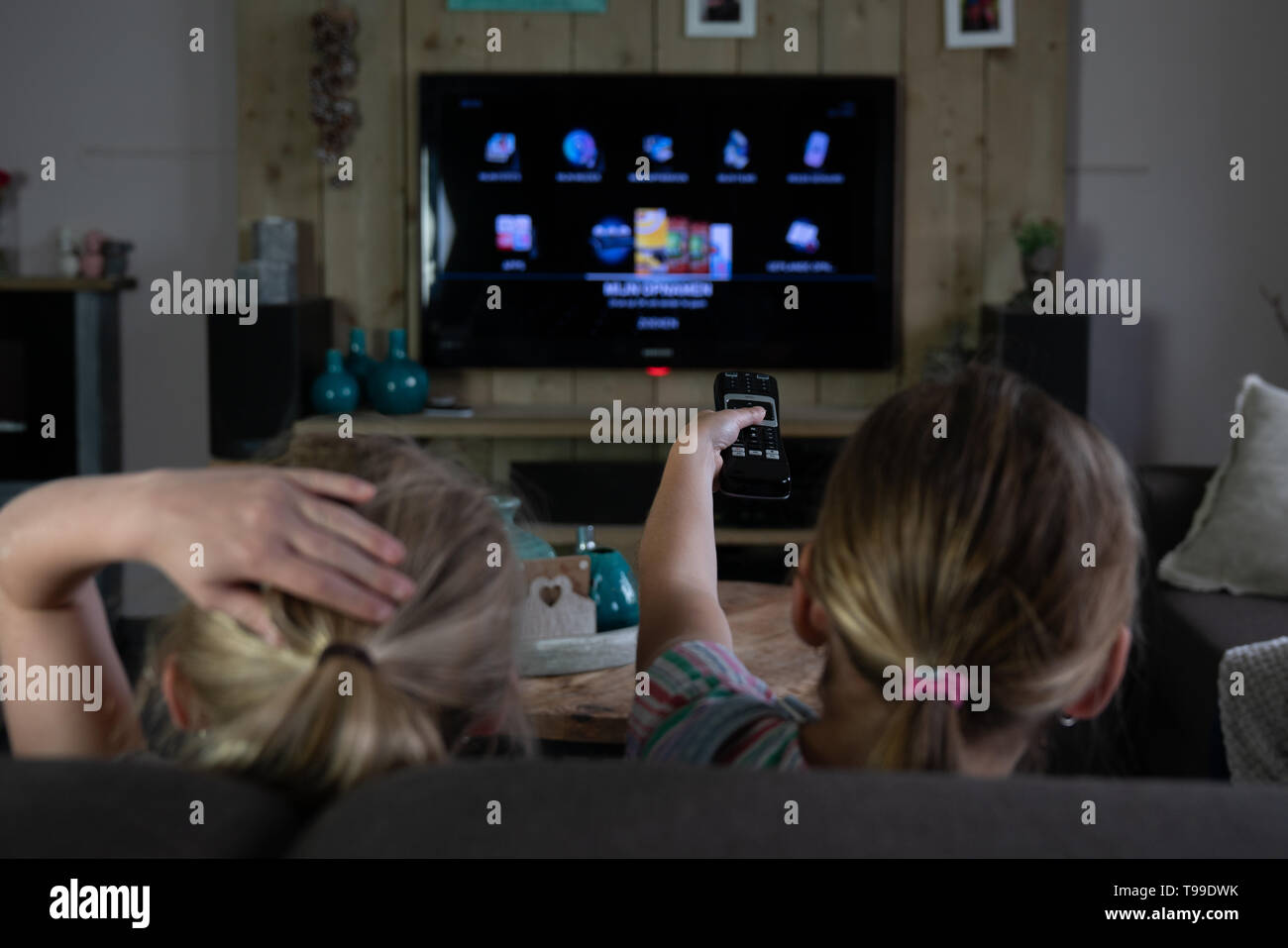 Vista posteriore dei due bambini di scorrimento attraverso le app su una smart tv. posteriore dei bambini con il focus sui bambini. Il futurismo quotidiana Foto Stock