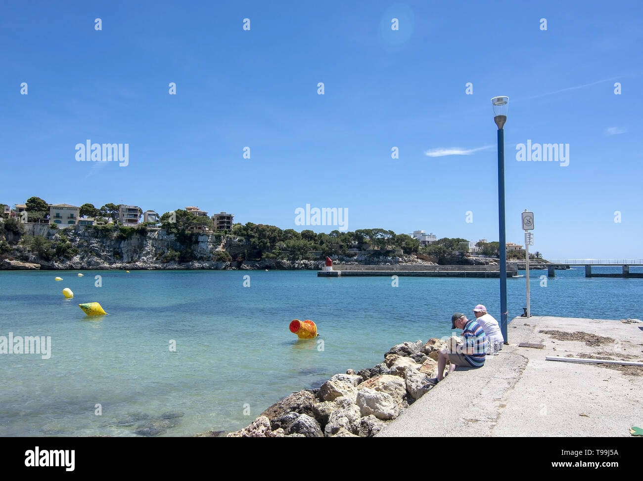 PORTO CRISTO, MALLORCA, Spagna - 16 Maggio 2019: giovane seduto sul molo in una giornata di sole su 16 Maggio 2019 in Porto Cristo, Mallorca, Spagna. Foto Stock