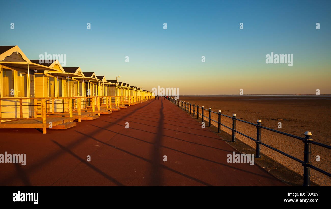 La prima serata sole sul lungomare di elementi in ferro battuto di ringhiere getta una lunga ombra lungo il centro della prom di fronte alla st annes beach capanne Foto Stock