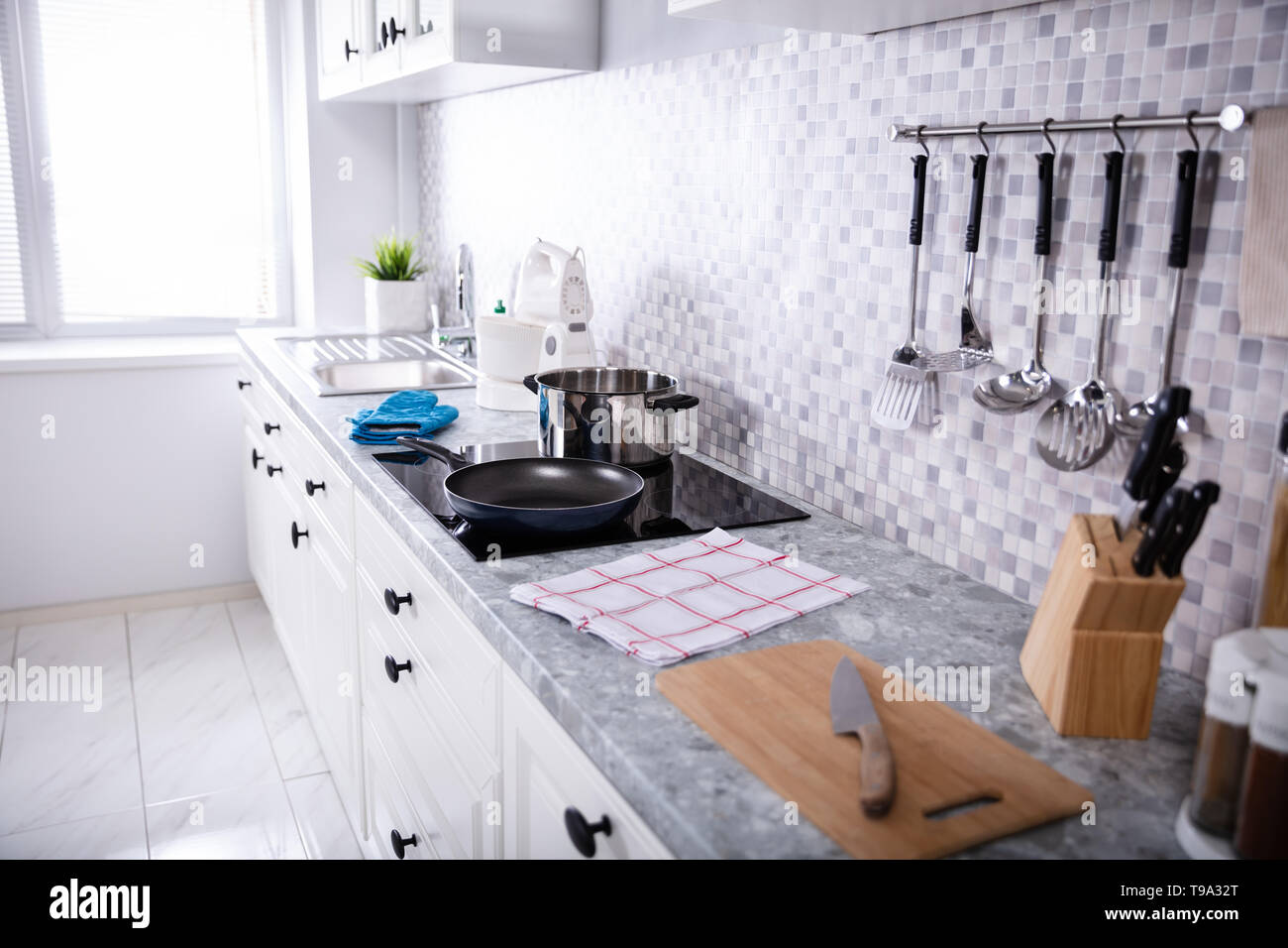 Vista di un moderno angolo cottura con utensili da cucina e fornelli a induzione Foto Stock