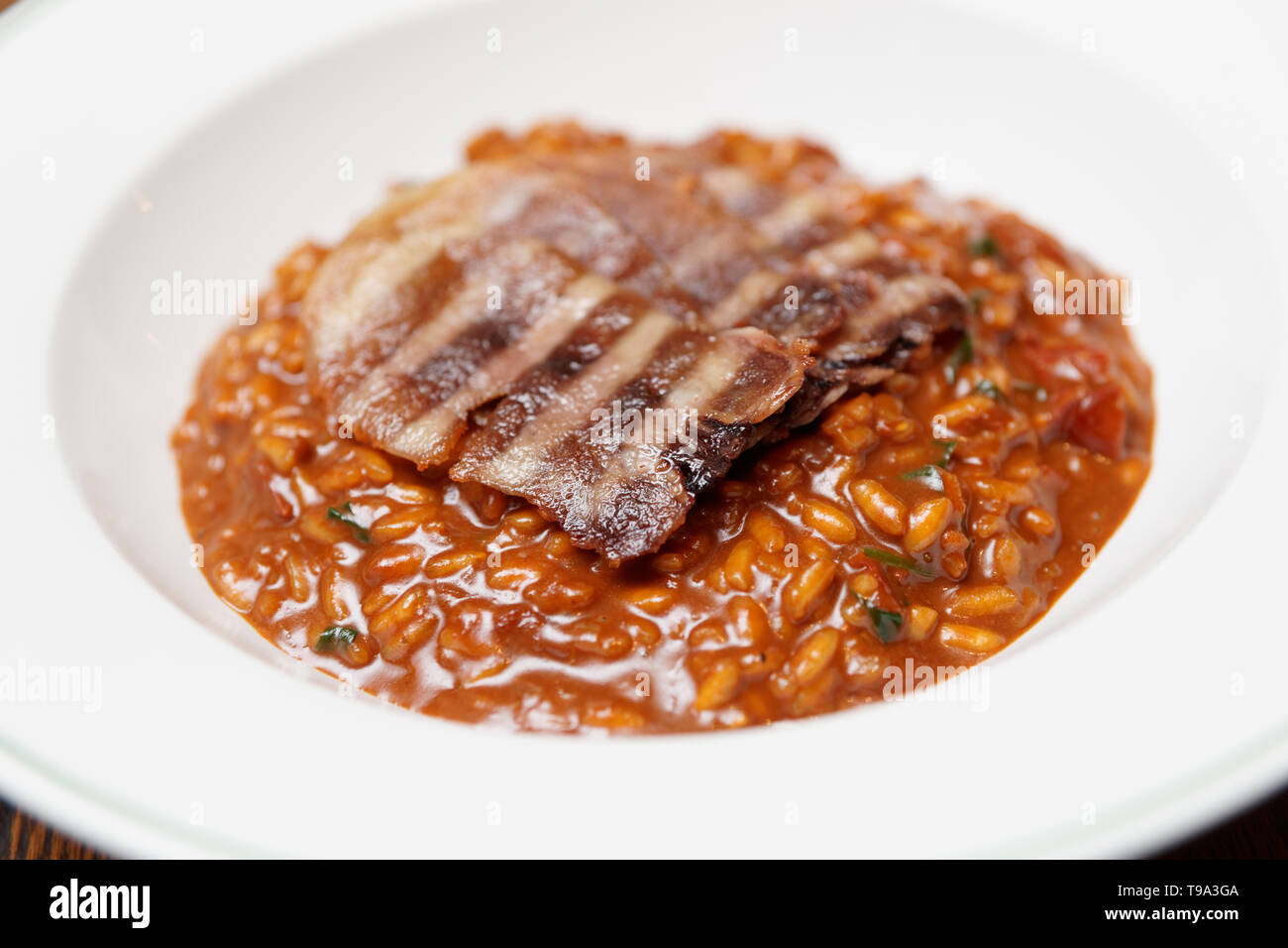 La segala risotto con grigliate di carne fette nel profondo la piastra di porcellana Foto Stock