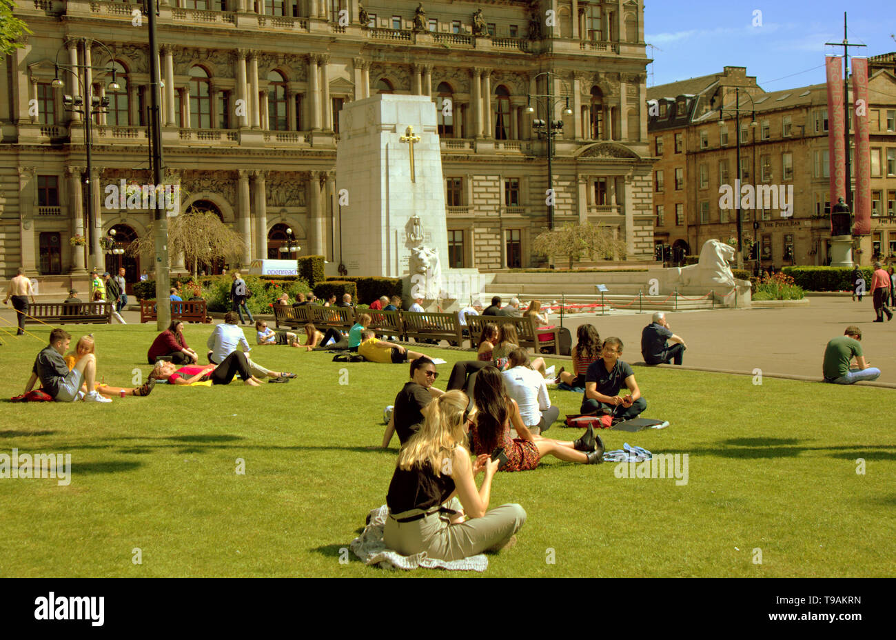 Glasgow, Scotland, Regno Unito, 17 maggio 2019, UK Meteo. Sunny scorcher di un giorno per la gente del posto e i turisti condividono l'erba con i piccioni nel centro civico della città George Square. Credito traghetto Gerard/Alamy Live News Foto Stock