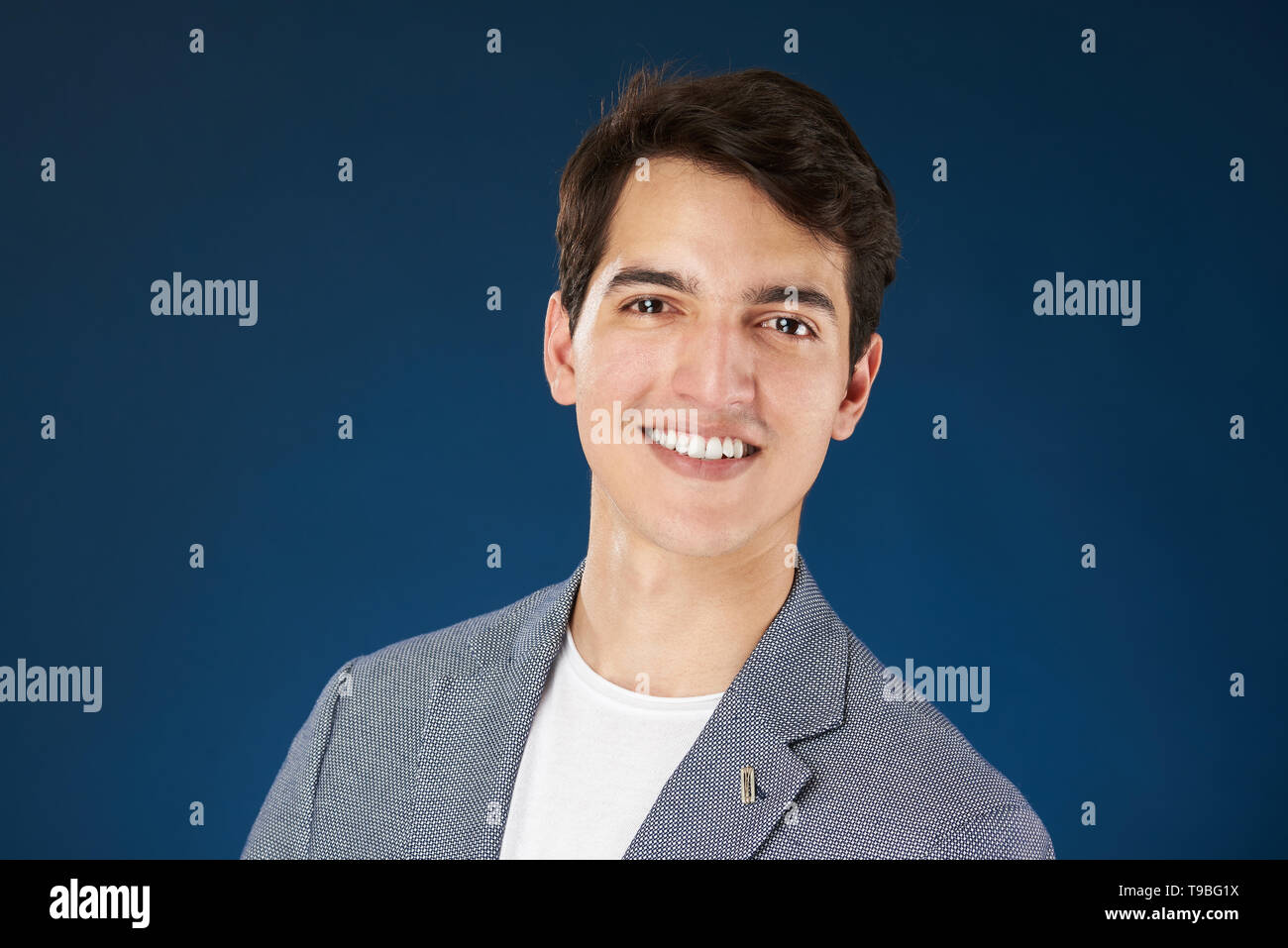 Headshot Ritratto di giovane uomo sorridente isolato su sfondo blu Foto Stock