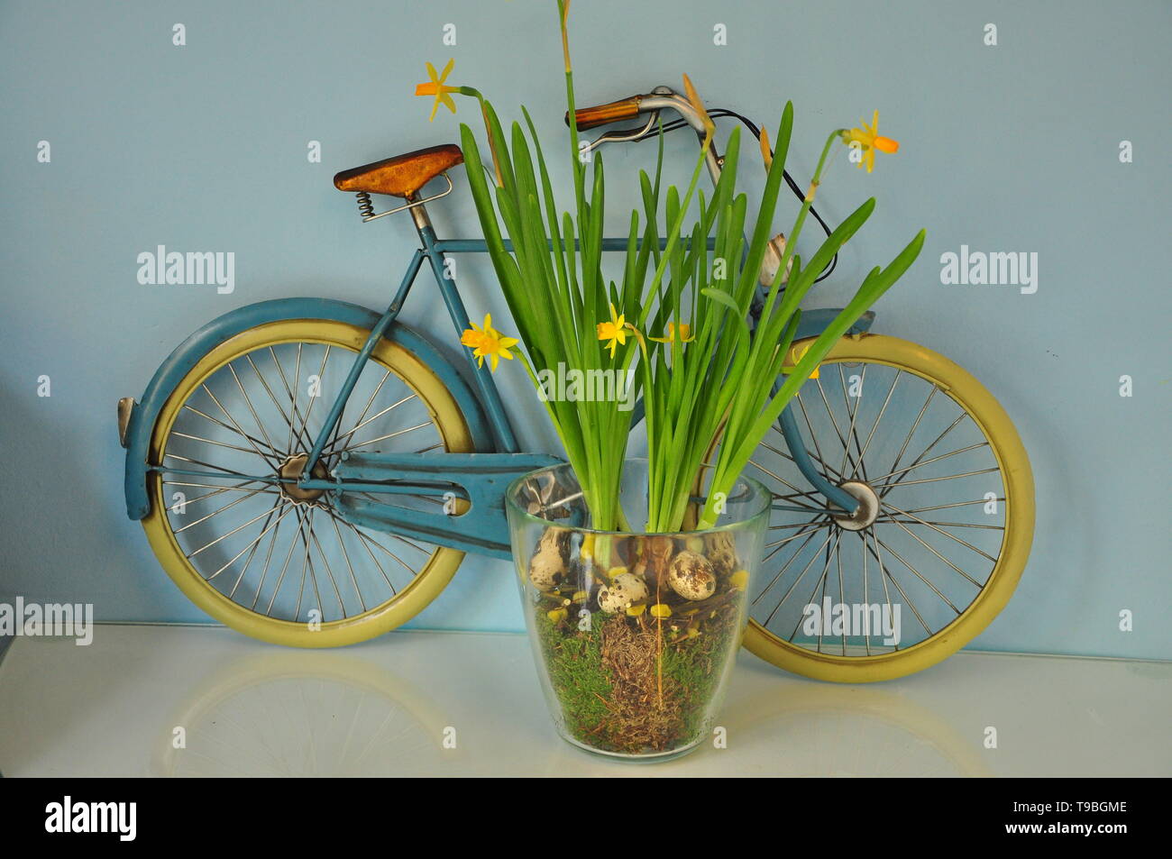 Chiudere fino a decorativi vintage giallo bicicletta con vaso di fiori fino contro la parete verde Foto Stock