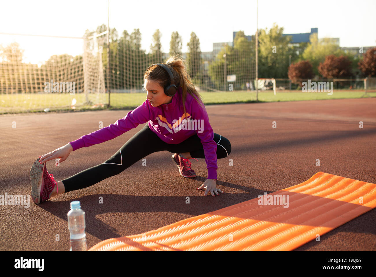 Giovane donna sportivo facendo esercizi sul tappeto in una giornata di sole Foto Stock