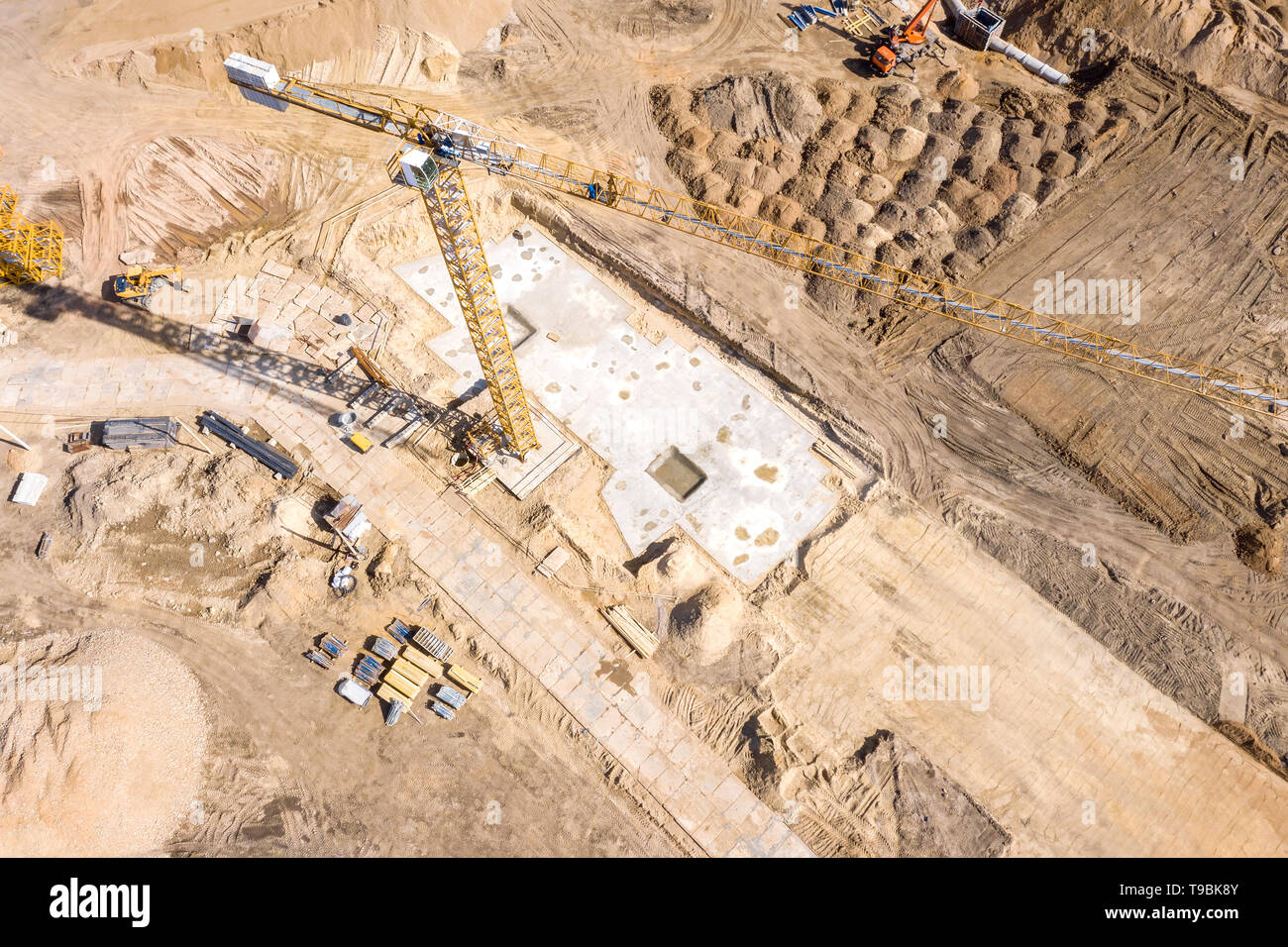 Vista aerea di lavori di fondazione su un sito in costruzione. gru a torre e macchine industriali per la costruzione di edifici Foto Stock