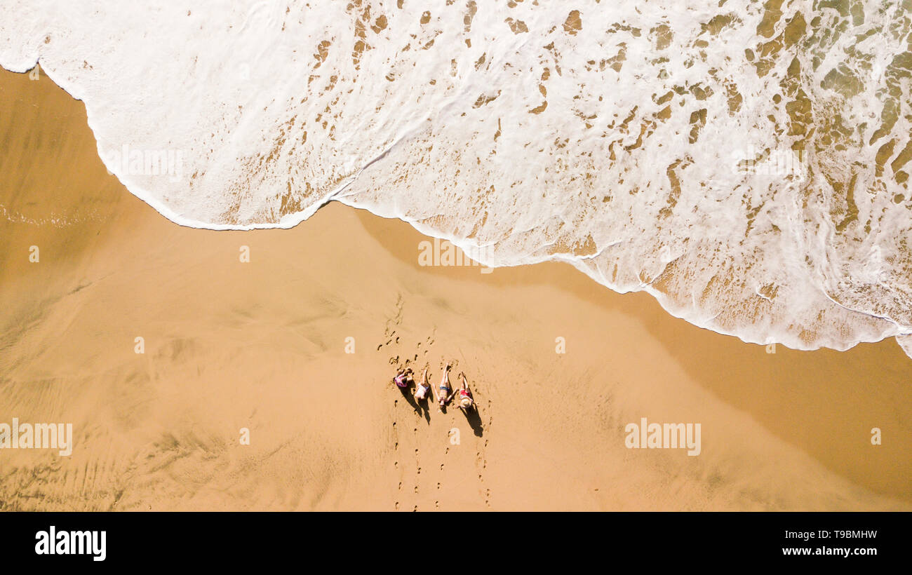 Antenna verticale vista di un gruppo di giovani amici godendo le vacanze estate vacanza in spiaggia con la grande onda prossimi - Splendida piscina natur Foto Stock