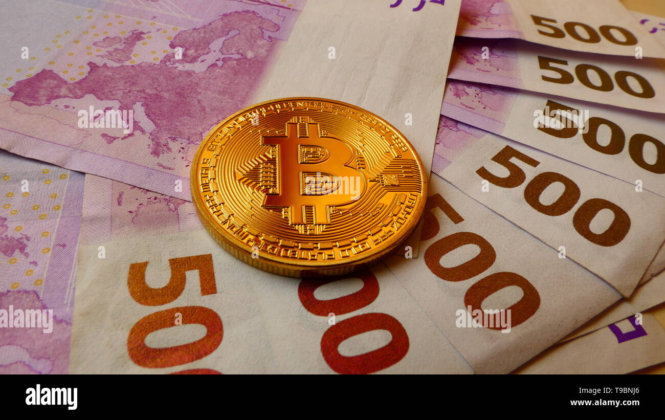 Bitcoins, una moneta virtuale in moneta fisica forma, visualizzato su 500 banconote in euro Foto Stock
