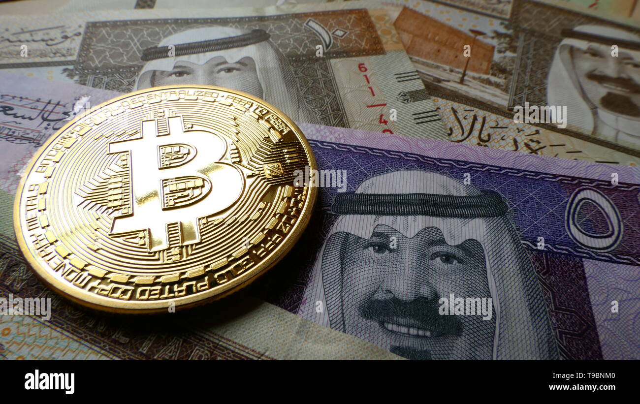 Bitcoin, una moneta virtuale in moneta fisica forma, visualizzato su Saudi Arabian Riyal banconote Foto Stock