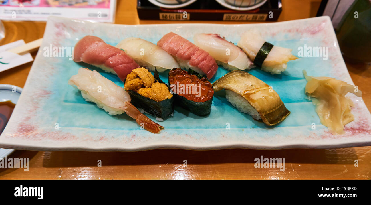 Piatto di una varietà di nigiri sushi e sushi rotoli (gunkan sushi) con alghe marine e zenzero sott'aceto (gari) sul lato al ristorante in Giappone. Foto Stock