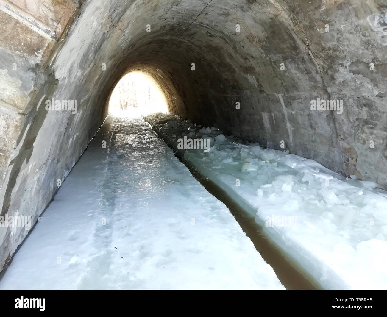 Ice tunnel del pavimento. Acqua congelata formata un gelido pavimento sotto il tunnel. Nel ghiaccio, tagliare un fosso per acqua Foto Stock Ice tunnel del pavimento. Acqua congelata formata un gelido pavimento sotto il tunnel. Nel ghiaccio, tagliare un fosso per acqua Foto Stock