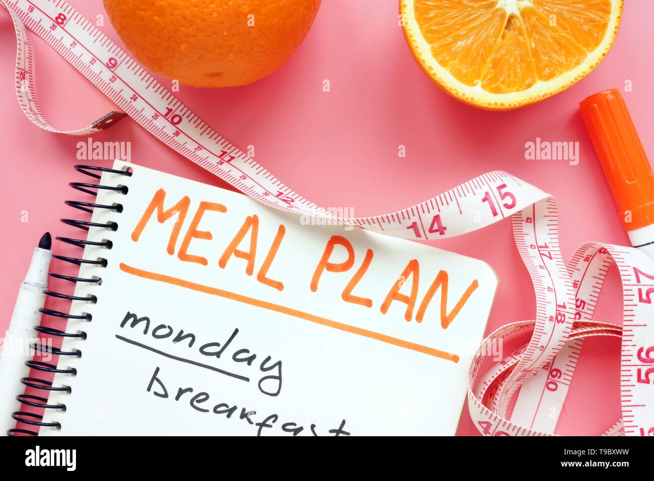 Servizio ristorazione per la perdita di peso con arancia sulla superficie di colore rosa. Foto Stock