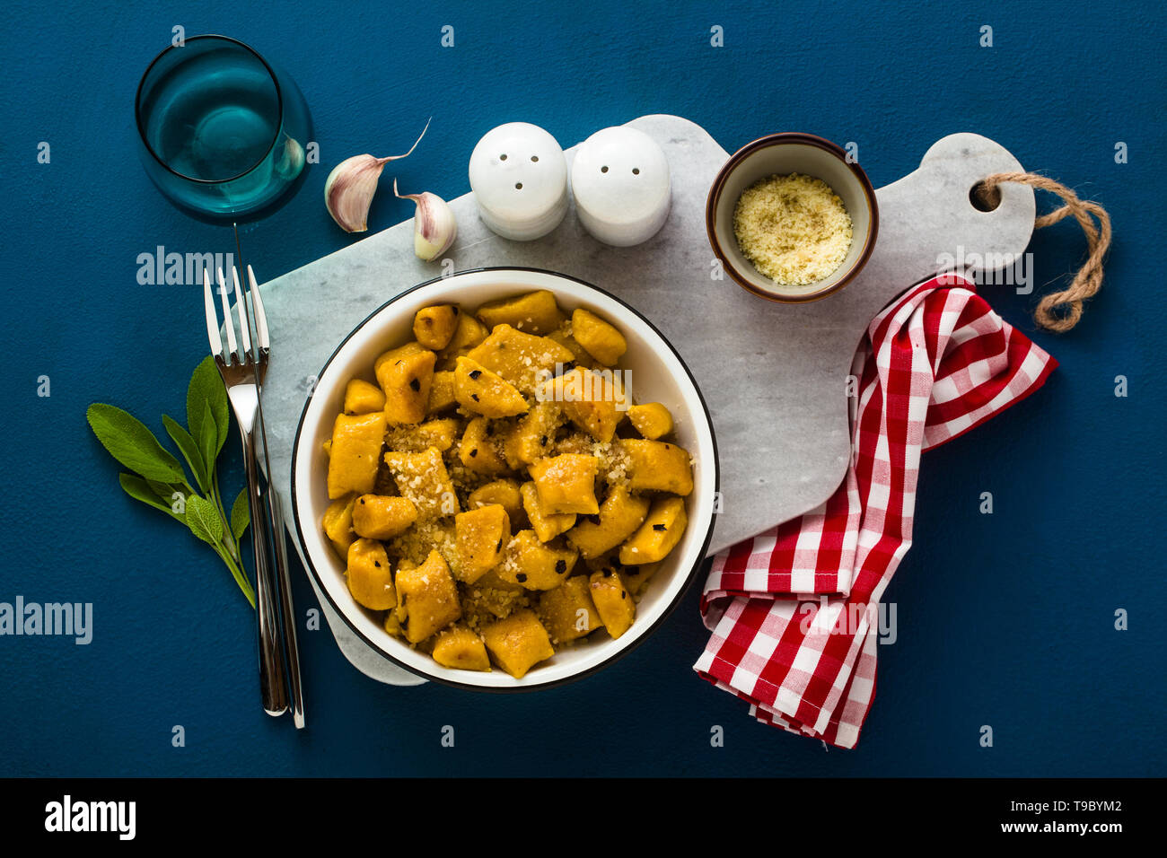 Italian gnocchi di zucca con parmigiano reggiano in una piastra su uno sfondo blu. piatti tradizionali Foto Stock