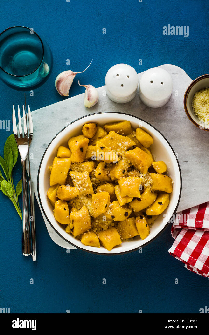 Italian gnocchi di zucca con parmigiano reggiano in una piastra su uno sfondo blu. piatti tradizionali Foto Stock