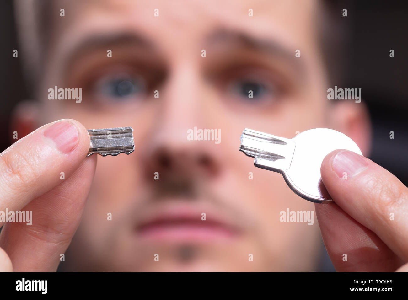 Ritratto di scioccato Man 's mano azienda argento chiave rotto Foto Stock