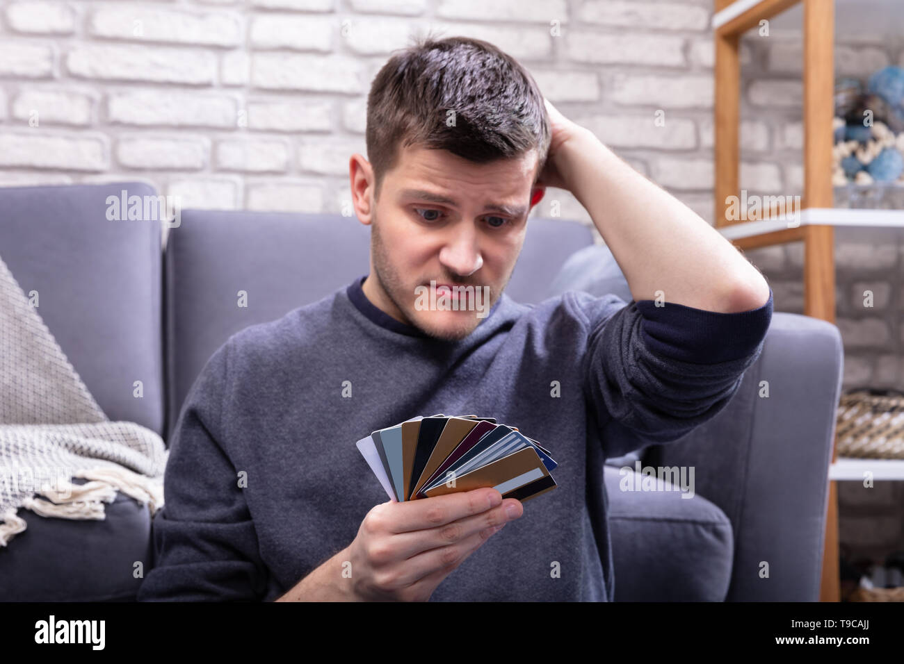 Ha sottolineato l'uomo Guardando troppo molte carte di credito in Home Foto Stock