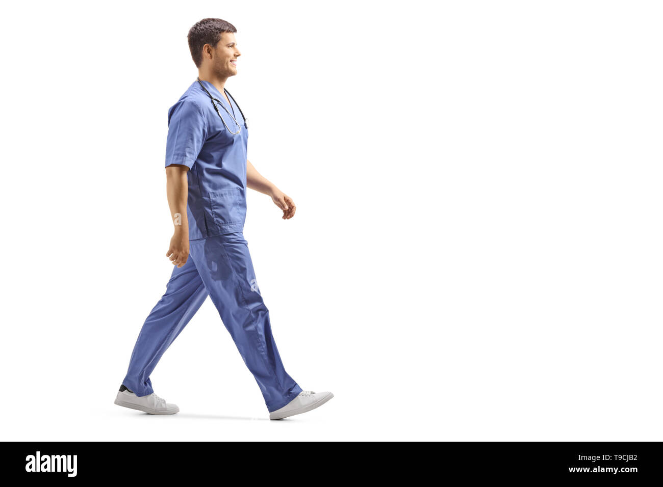 Lunghezza piena ripresa del profilo di un giovane maschio medico in uniforme blu pochi isolati su sfondo bianco Foto Stock