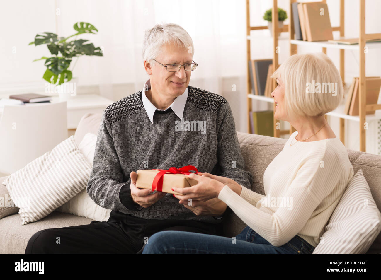 Senior donna dando presente al marito a casa Foto Stock