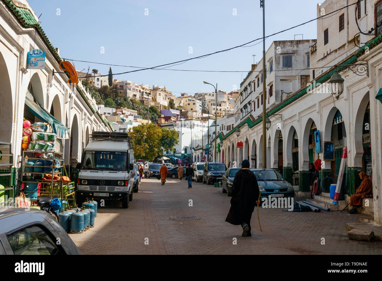 Persone non identificate a piedi lungo la strada principale di Moulay Idriss in una giornata di sole. Moulay Idriss Zerhoun, Marocco. Foto Stock