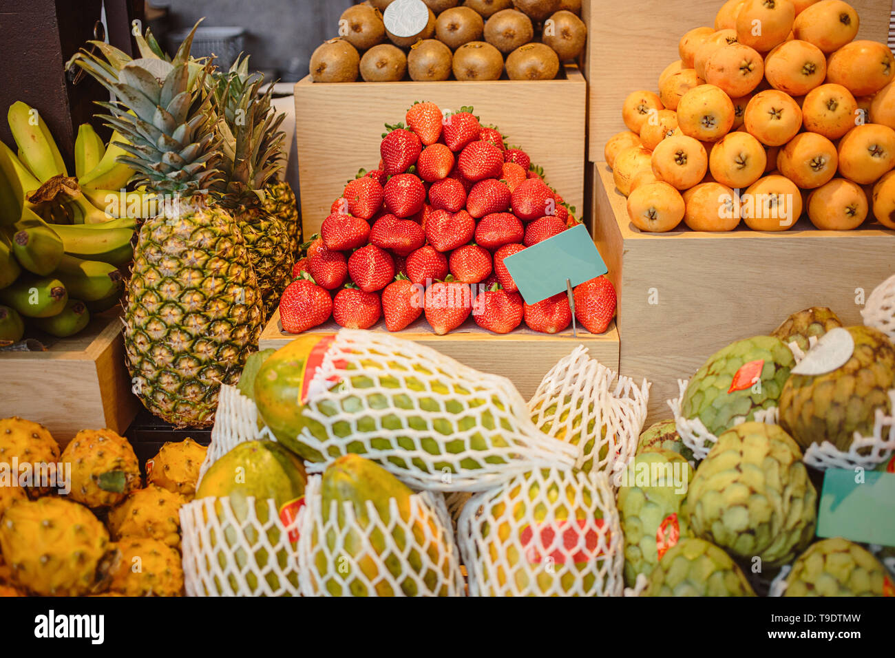 Fragola, ananas, banana, kiwi, persimmon sono venduti sul bancone di un negozio di frutta sulla strada di Madrid. Diversi tipi di frutta sono stabiliti sul contatore. Foto Stock