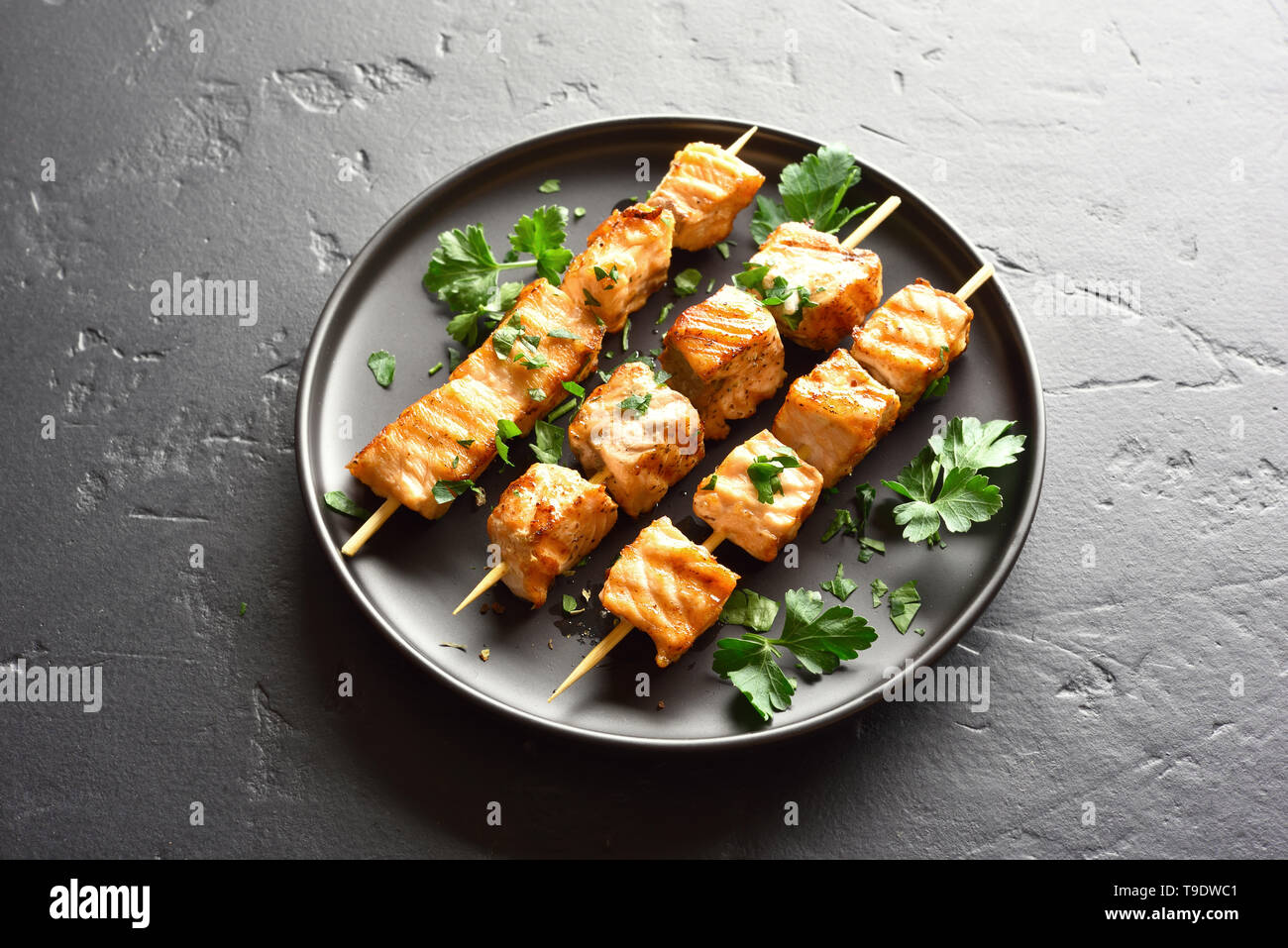 Salmone alla griglia kebab. Barbecue spiedini di salmone su pietra nera dello sfondo. Foto Stock