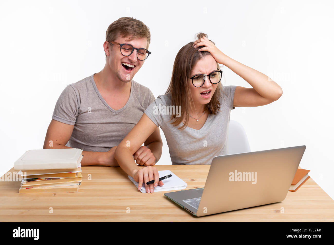 Le persone e il concetto di istruzione - Due happy funny studenti seduti al tavolo di legno con laptop e libri Foto Stock