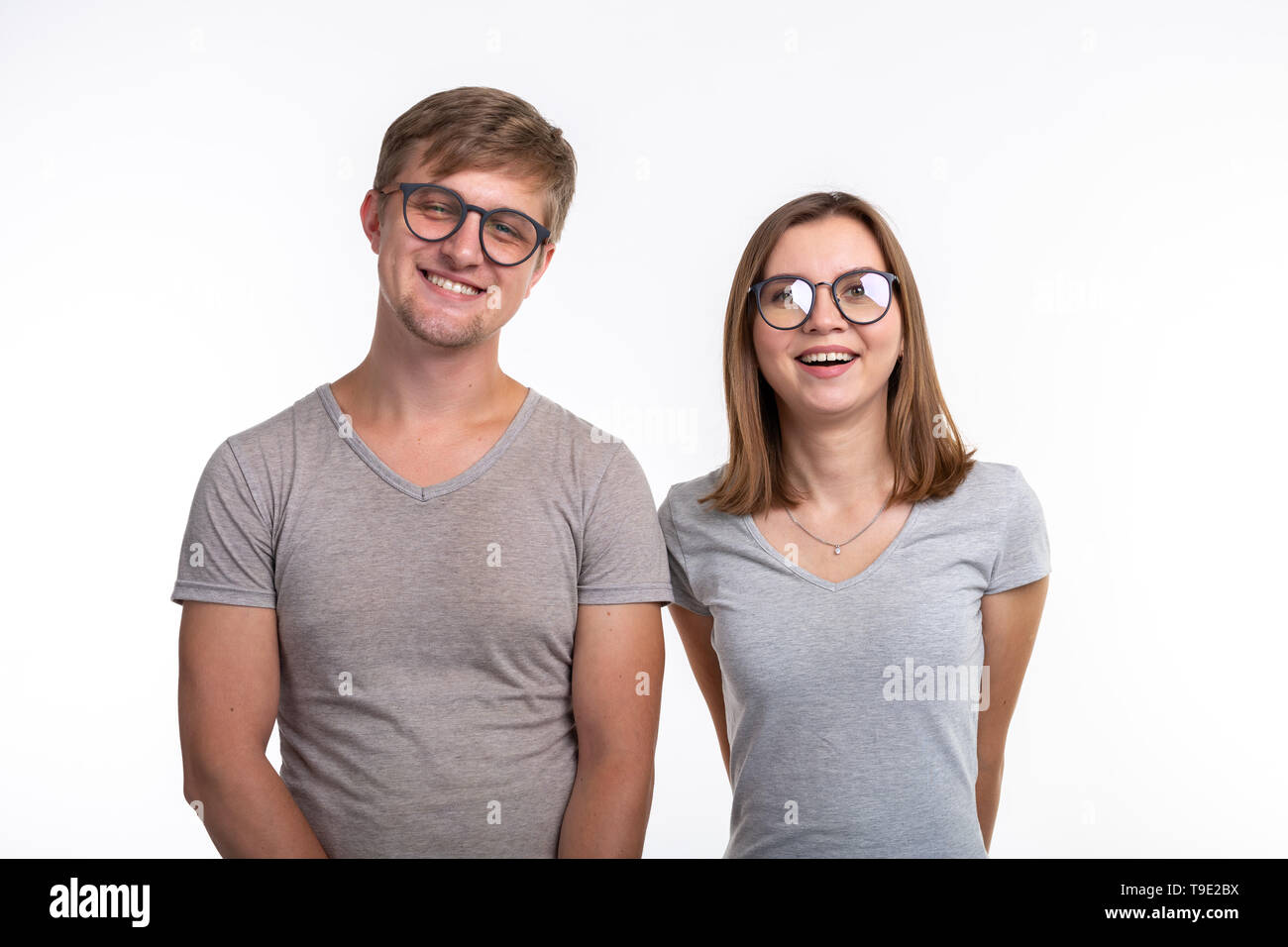 Le persone e il concetto di istruzione - Due giovani studenti divertenti con premurosa si affaccia su sfondo bianco Foto Stock